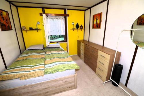 a bedroom with a bed and a yellow wall at Chata Skřinářov 