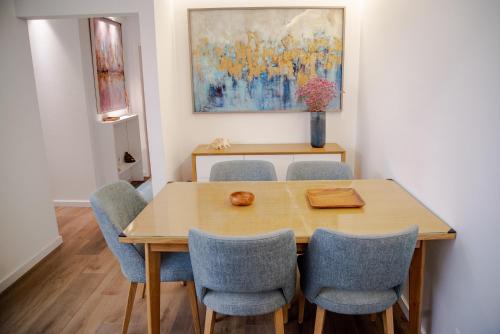 einen Esstisch mit Stühlen und ein Gemälde in der Unterkunft Apartamento Fragosa - Vieira's Mar in Póvoa de Varzim