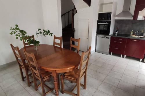 a kitchen with a wooden table and chairs in a room at Relais de l'écurie Heuse in Cambremer