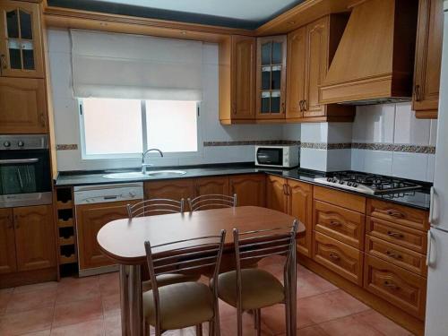 eine Küche mit Holzschränken sowie einem Tisch und Stühlen in der Unterkunft apartamento céntrico en Lorca in Lorca