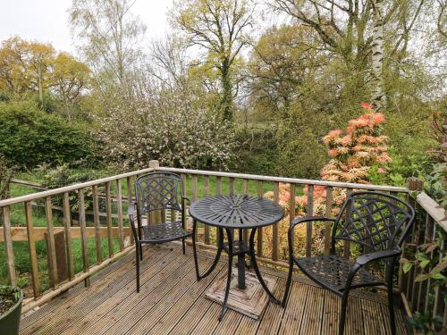 a table and two chairs on a wooden deck at Woodstock Retreat in Axminster
