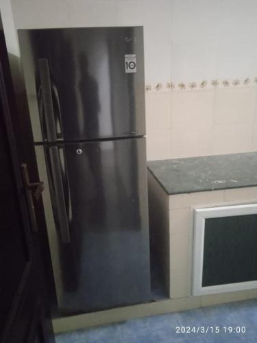 een zwarte koelkast in een keuken naast een magnetron bij Wajood Services Apartment بناية وجود للشقق الفندقية in Salalah