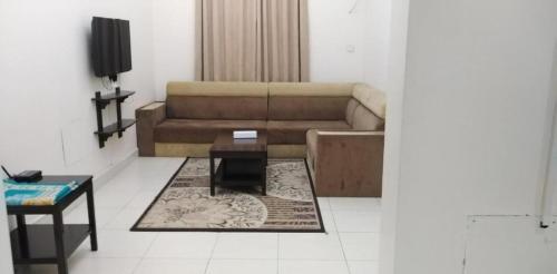 een woonkamer met een bank en een salontafel bij Wajood Services Apartment بناية وجود للشقق الفندقية in Salalah