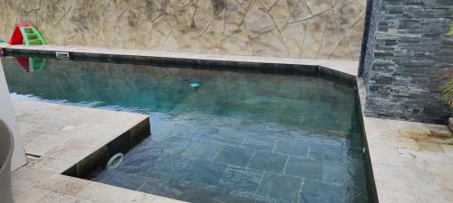 a pool of water with a brick wall and a swimming pool at Villa Mary Guest House in Saint-André