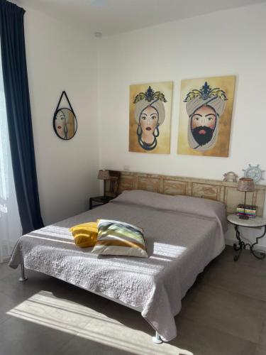 a bedroom with a bed with three paintings on the wall at EcoCasa Neapolis in Siracusa