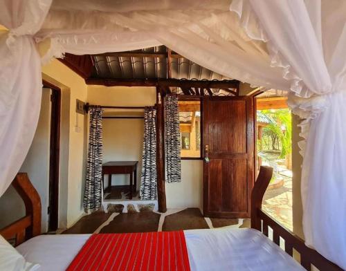 1 dormitorio con cama con dosel y sofá en Kijani Cottages - In Diani en Diani Beach