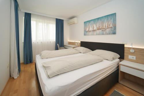 a bedroom with a large bed with white sheets at Garden Palace Pool Deluxe Apartment in Umag