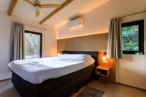a bedroom with a large bed and two windows at La Picolla Bellezza in Mandelieu-la-Napoule