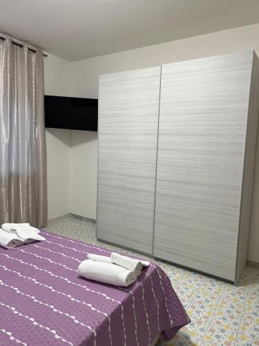 una camera da letto con un letto viola e asciugamani di VERA'S HOUSE a Napoli