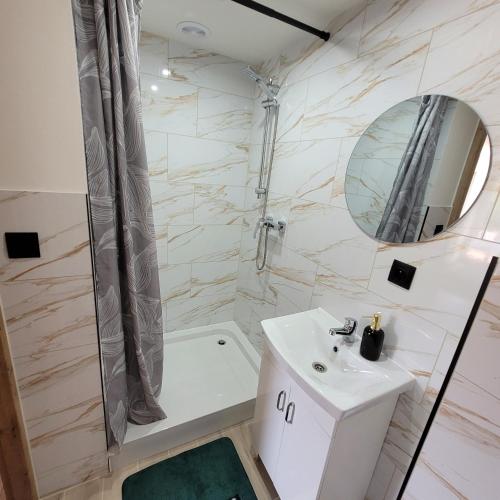 a white bathroom with a sink and a shower at Pokoje Gościnne Baśniowy Dom Radków in Wünschelburg