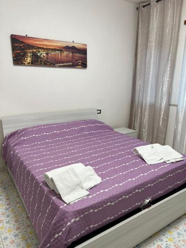una camera da letto con un letto viola e asciugamani di VERA'S HOUSE a Napoli