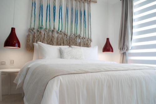 a bedroom with a white bed with two red lamps at Sabbia By LD Hoteles in El Roque