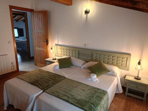 a bedroom with a large white bed with green pillows at LA CASITA DEL CARRETERO in Bercimuel