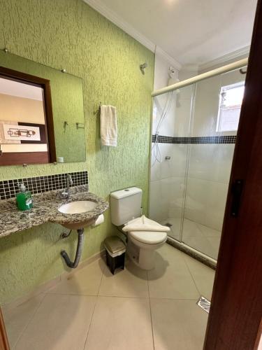 a bathroom with a toilet and a sink and a shower at Pousada Werneck Residence Suites in Ubatuba