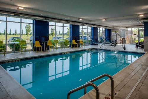 a swimming pool in a hotel with tables and chairs at Home2 Suites By Hilton Northville Detroit in Northville