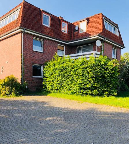 a red brick building with a red roof at Nordsee Terrasse in Hooksiel