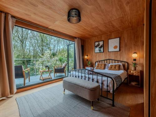 um quarto com uma cama e uma grande janela em Pass the Keys Acorn Lodge · Luxury Retreat In a Stunning Oasis With Hot Tub em Market Drayton