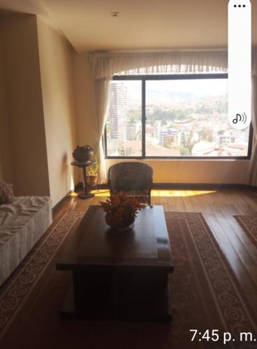 uma sala de estar com uma mesa e uma grande janela em Aidee em La Paz