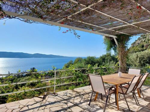 einen Tisch und Stühle auf einer Terrasse mit Blick auf das Wasser in der Unterkunft Villa Tramonto in Lévki