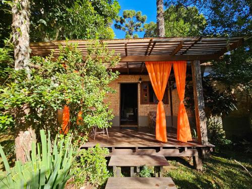 a wooden pergola with a table and benches in a garden at Estalagem Wiesbaden in Monte Verde