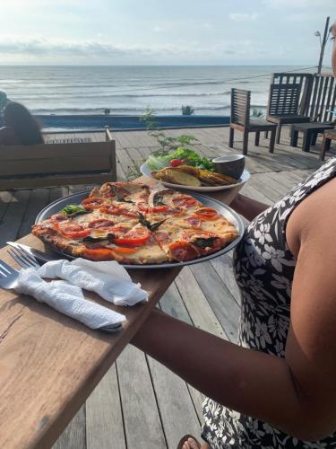 una mujer está sentada en una mesa con una pizza en Casa heysol en Bahía de Caráquez