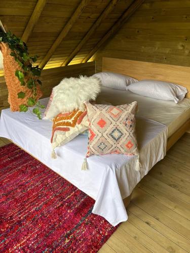 a bed with pillows on it with a rug at Cabañas Colibrí in Cocorná