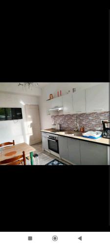 une cuisine avec des armoires blanches et une table en bois dans l'établissement Chez Paulette, à Vendôme