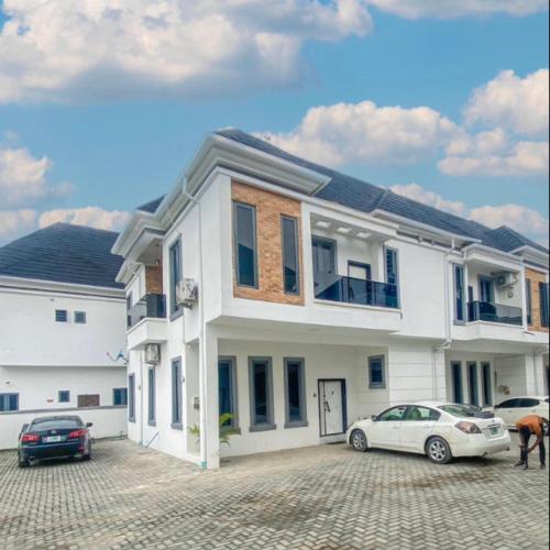 une maison blanche avec deux voitures garées dans un parking dans l'établissement 3Bedroom Serviced Apartment Shortlet, Lekki- Lagos, à Lekki