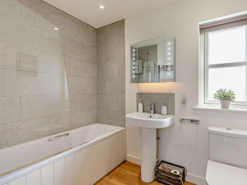 uma casa de banho com uma banheira, um lavatório e uma banheira tubermottermott em 2 Bed in Bamburgh 90061 em Chatton