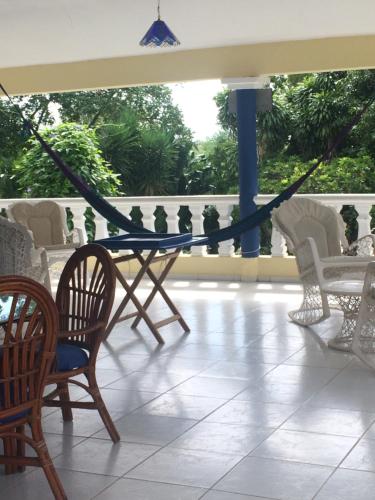 a table and chairs on a porch with a hammock at Sana El Jardin Secreto in Santiago de los Caballeros