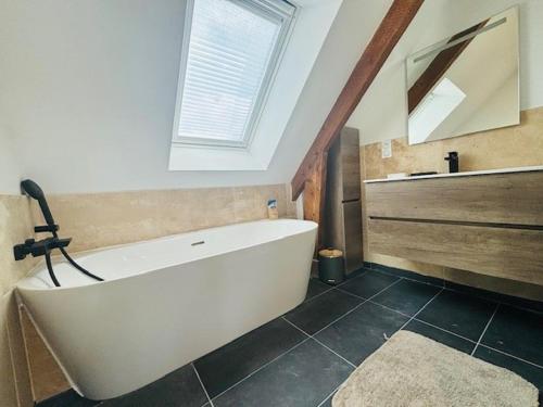 a large white bath tub in a bathroom with a window at Les Chênes en duplex in Ploemeur