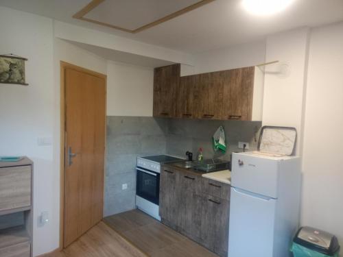 a kitchen with a white refrigerator and a stove at Vila Tutić Apartman 1 i Apartman 2 in Mitrovac