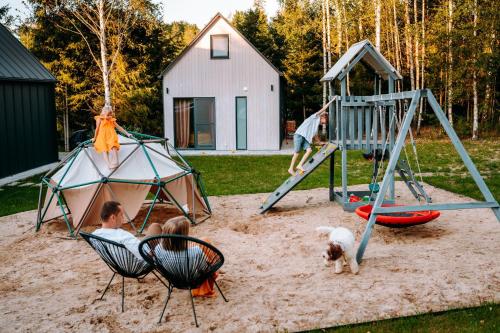 een groep mensen en een hond die op een speelplaats speelt bij Żywiołowo - domki w stylu stodoły z placem zabaw i stawem - OGIEŃ in Parchowo