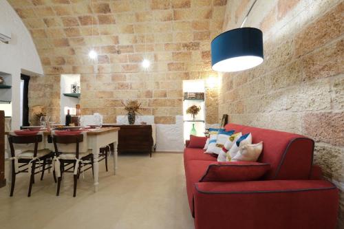 a living room with a red couch and a table at Casina Li Fumareddhi in Corsano