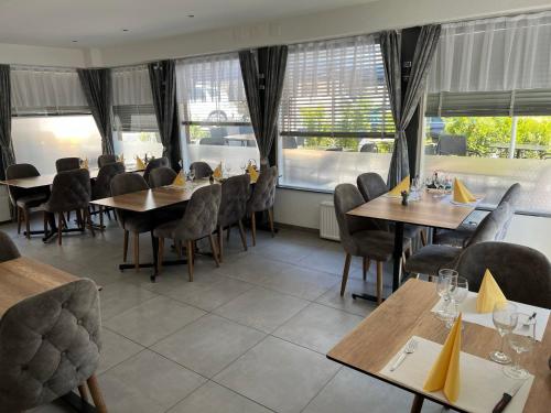 um restaurante com mesas e cadeiras de madeira e janelas em Hotel Restaurant du Moulin em Fleurier