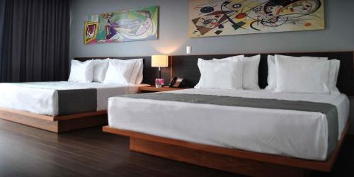 2 łóżka w pokoju hotelowym z białymi poduszkami w obiekcie Hotel y Tú Expo w mieście Guadalajara