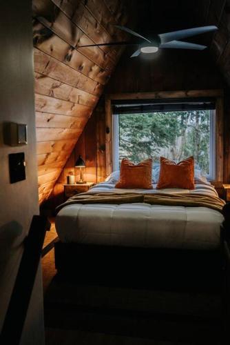a bedroom with a bed with two pillows and a window at NEW! Cozy & Modern A-Frame in the woods w/HOT TUB in Tamworth