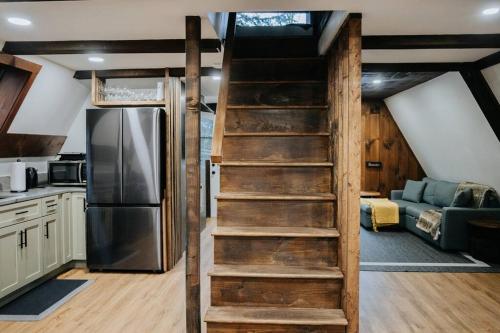 a staircase leading to a kitchen with a refrigerator at NEW! Cozy & Modern A-Frame in the woods w/HOT TUB in Tamworth