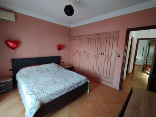 a bedroom with a bed and a pink wall at Naila in Sidi Bouzid