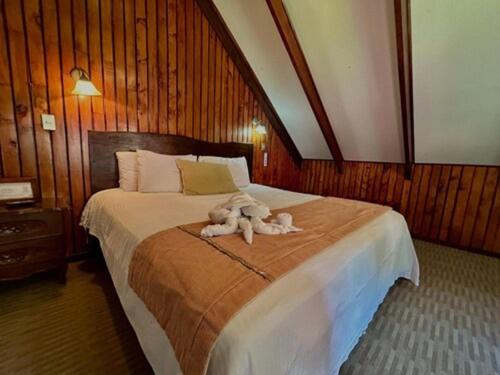 un animal de peluche sentado encima de una cama en Hotel El Tirol en Alto del Roble