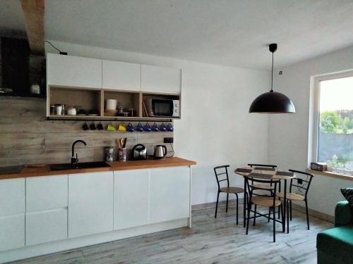 een keuken met witte kasten en een tafel met stoelen bij AdMi in Krasnobród