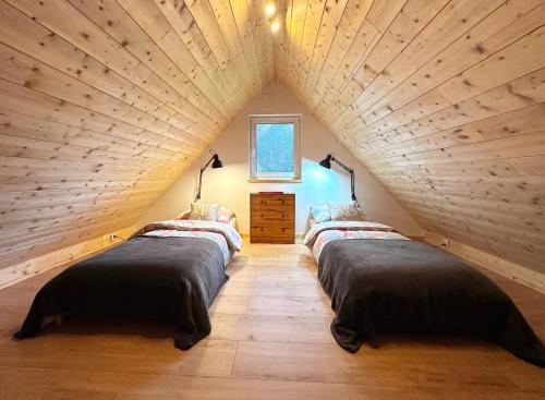 a attic bedroom with three beds in a room at Żywiołowo - domki w stylu stodoły z placem zabaw i stawem - OGIEŃ in Parchowo