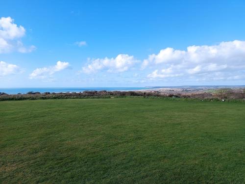 un champ vert vide avec l’océan à l’arrière-plan dans l'établissement Camping Les Ronds Duval face aux îles anglo-normandes, à Les Moitiers-dʼAllonne