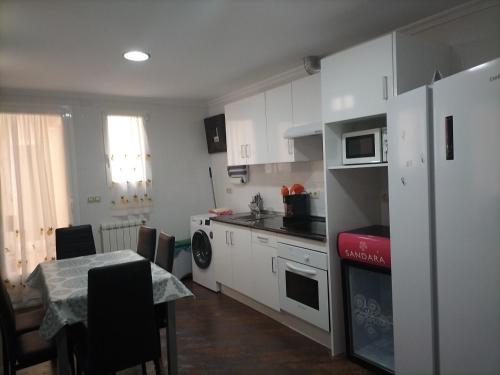 cocina con armarios blancos, mesa y comedor en Casa Vila, en Riópar