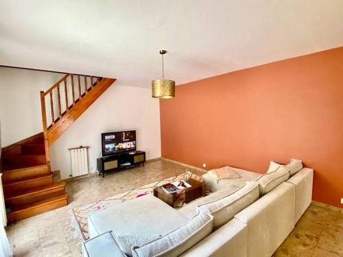 a living room with a white couch and a staircase at Superbe Maison à Saint-Ouen in Saint-Ouen