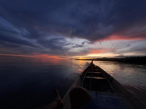 osoba w łodzi na wodzie o zachodzie słońca w obiekcie Maricho Homestay w mieście Besir
