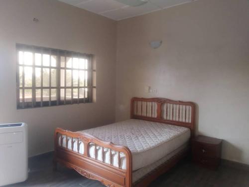 a bedroom with a wooden bed and two windows at Fidjrossé Beach in Cotonou
