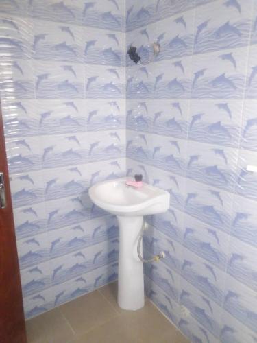 baño con lavabo y pared con estampado de tiburones en Fidjrossé Beach en Cotonú