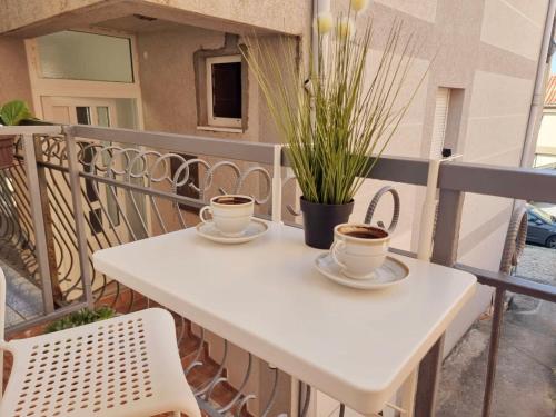 two cups of coffee on a white table on a balcony at Studio apartman na plaži in Rafailovici