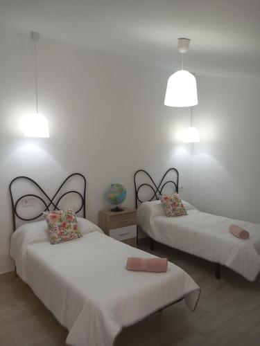 two beds in a room with white walls and lights at EL RINCON DEL ROMERAL in Pegalajar